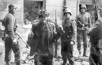 חיילים נאצים עוצרים יהודי בגטו ורשה ב-1943 (צילום: איי פי)